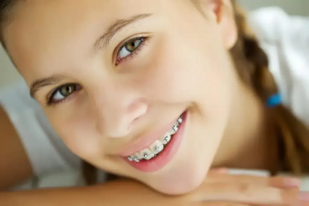 A young girl with braces is smiling for the camera.