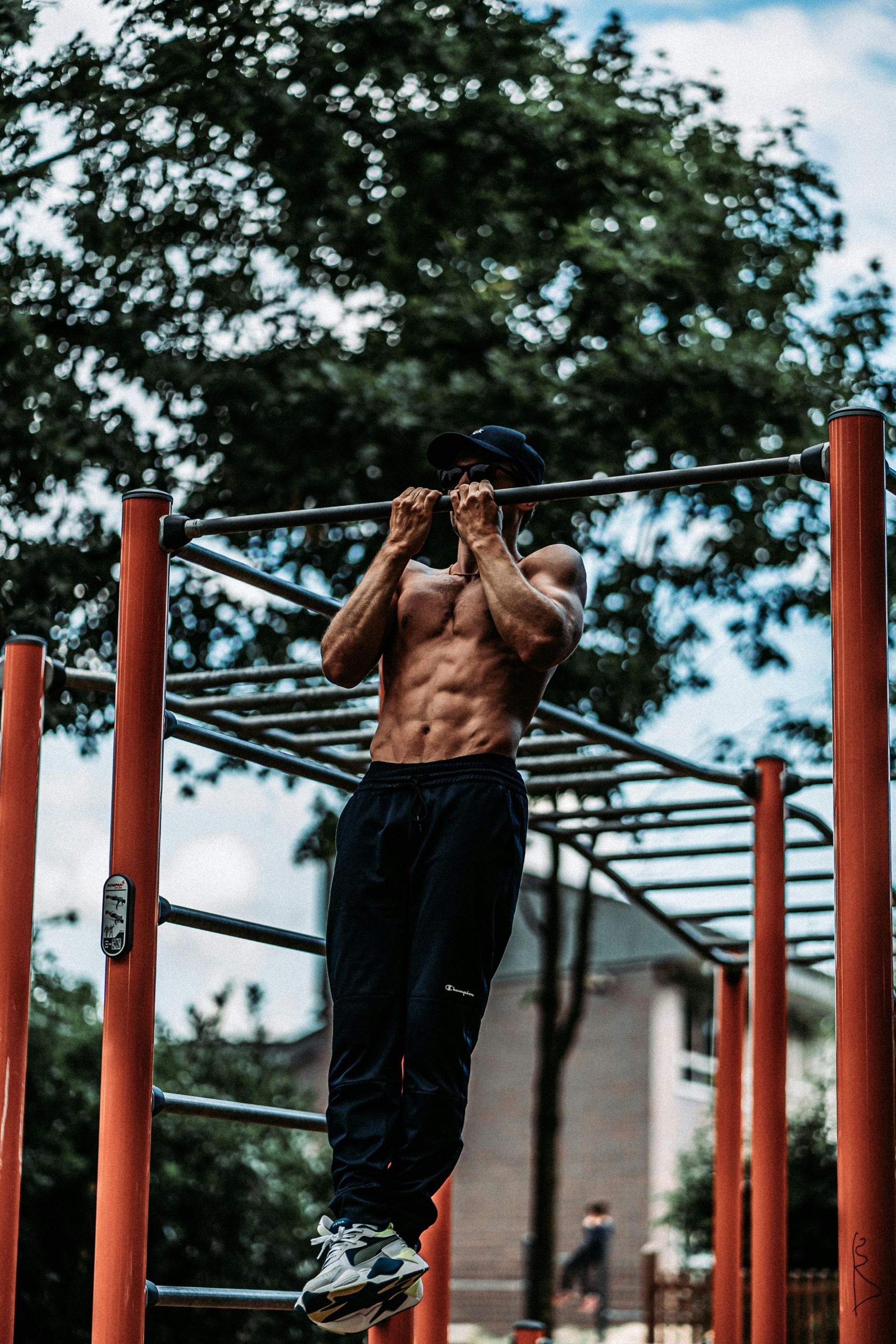 Man doing a pull-up on red outdoor bars in a park