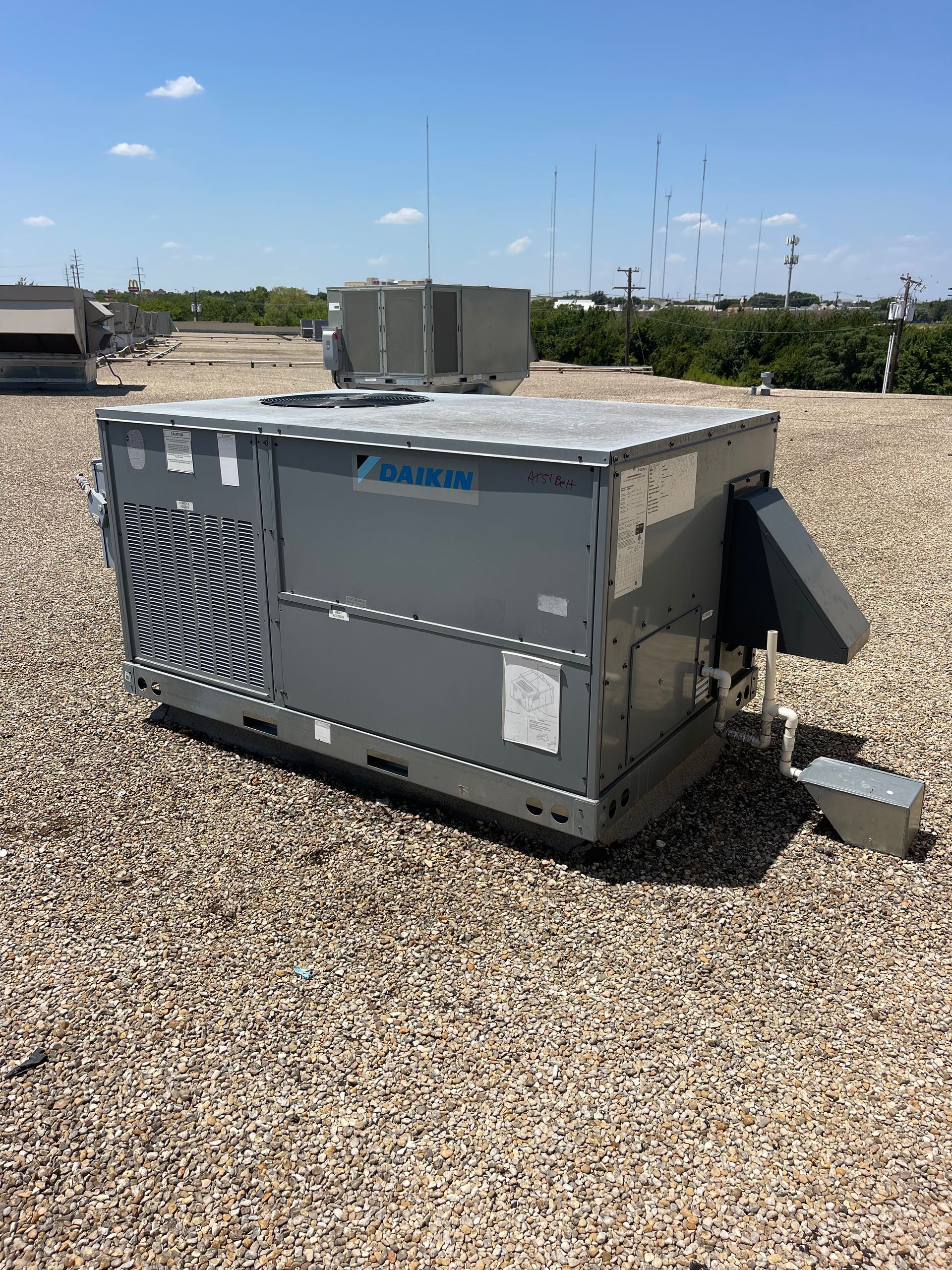 a large gray box is sitting on top of a gravel covered roof .