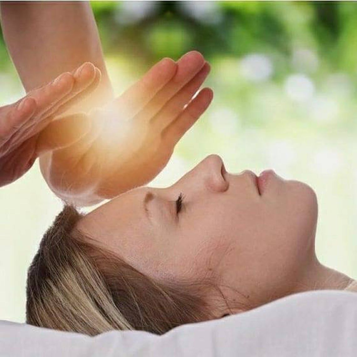 a woman is getting a healing session with a person 's hand on her forehead .