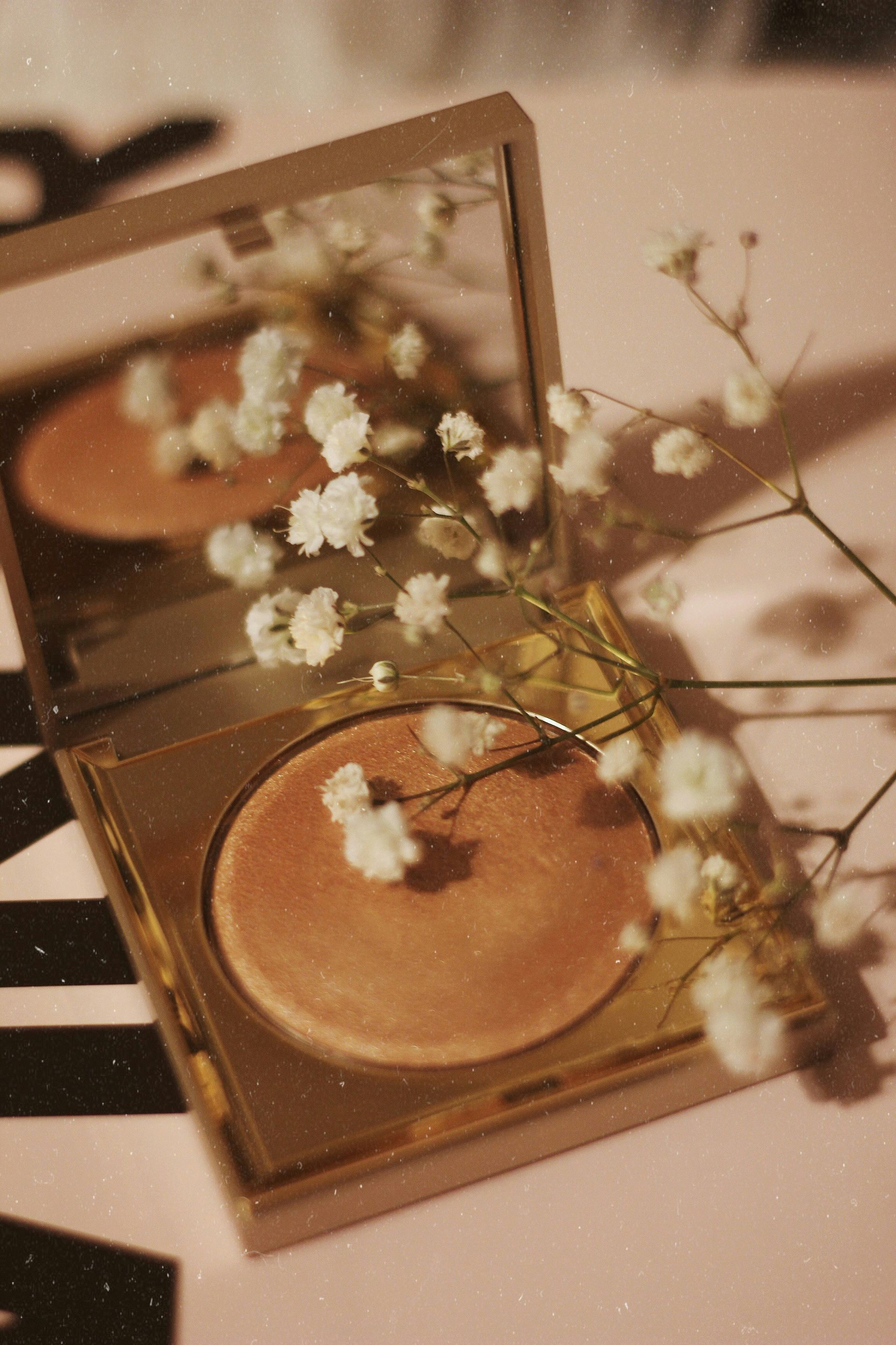 A powder sitting on top of a table next to a mirror and flowers.