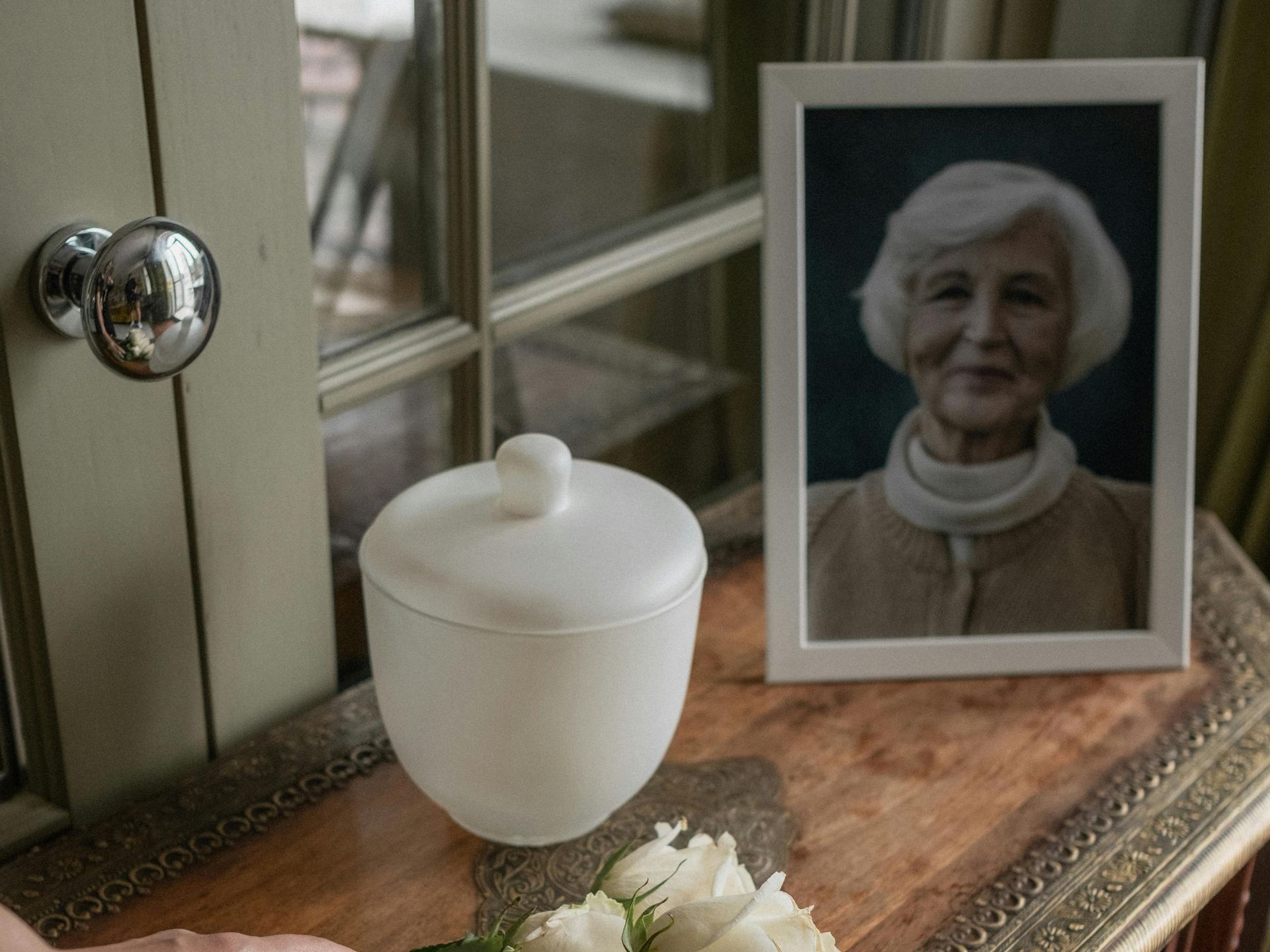 A picture of an elderly woman is sitting on a table next to a vase of flowers.