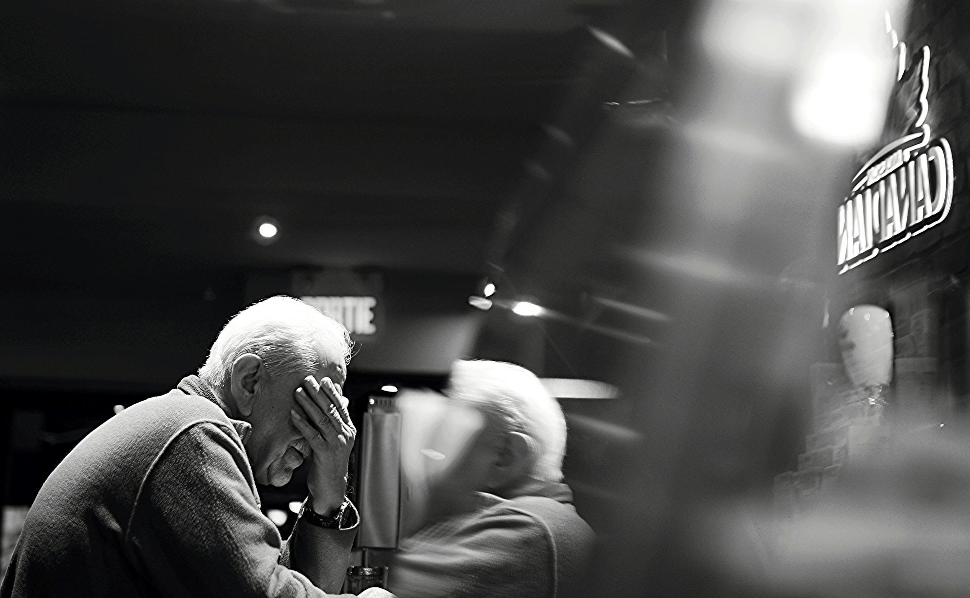 A black and white photo of two men sitting at a table in a bar.