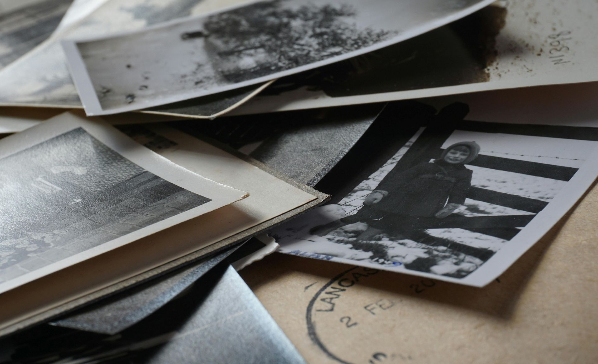 A pile of old black and white photographs on a table