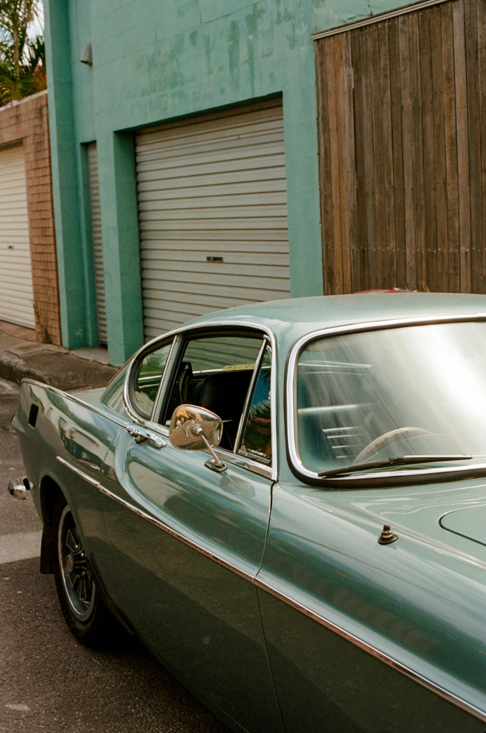 A blue car is parked in front of a garage.