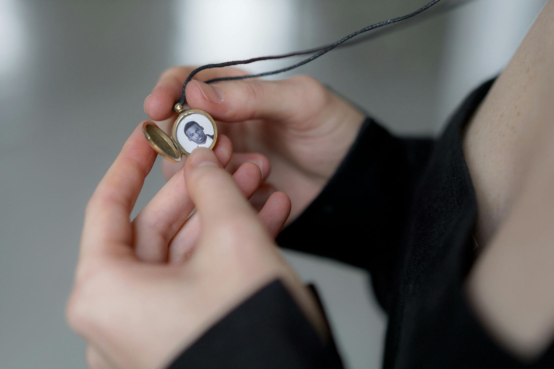 A person is holding a locket with a picture of a man on it.