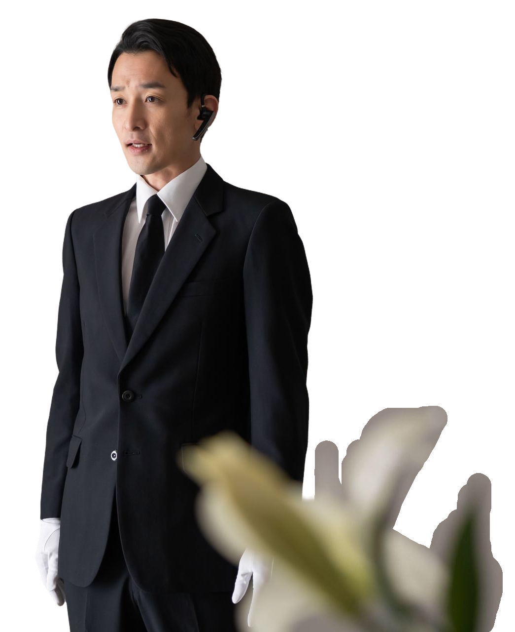 A man in a suit and tie is standing next to a flower.