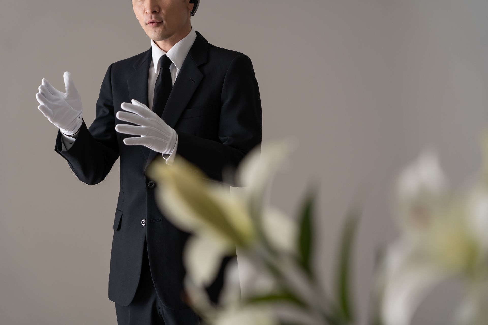 A man in a suit and tie is wearing white gloves.