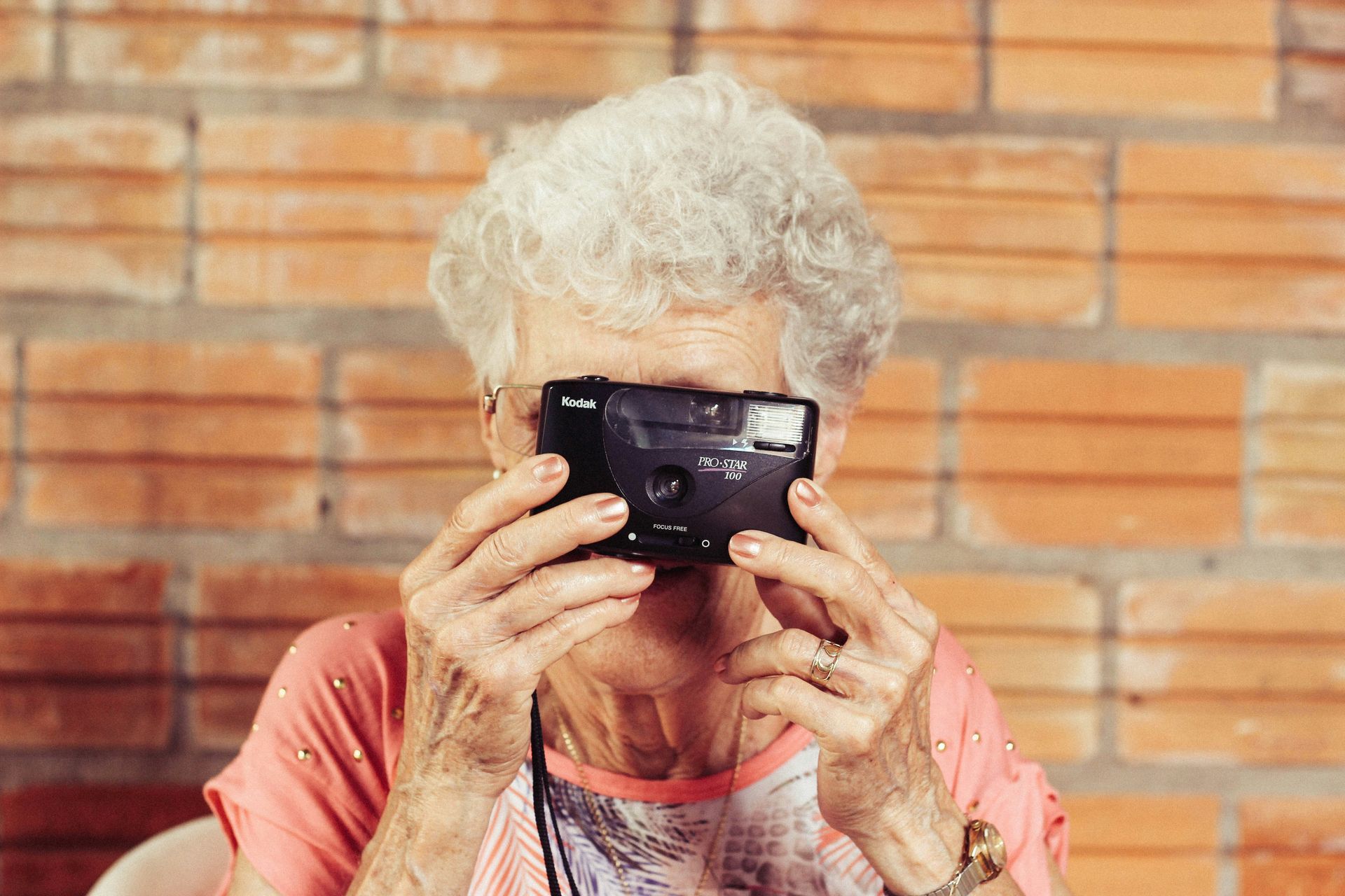 An elderly woman is taking a picture with a camera.