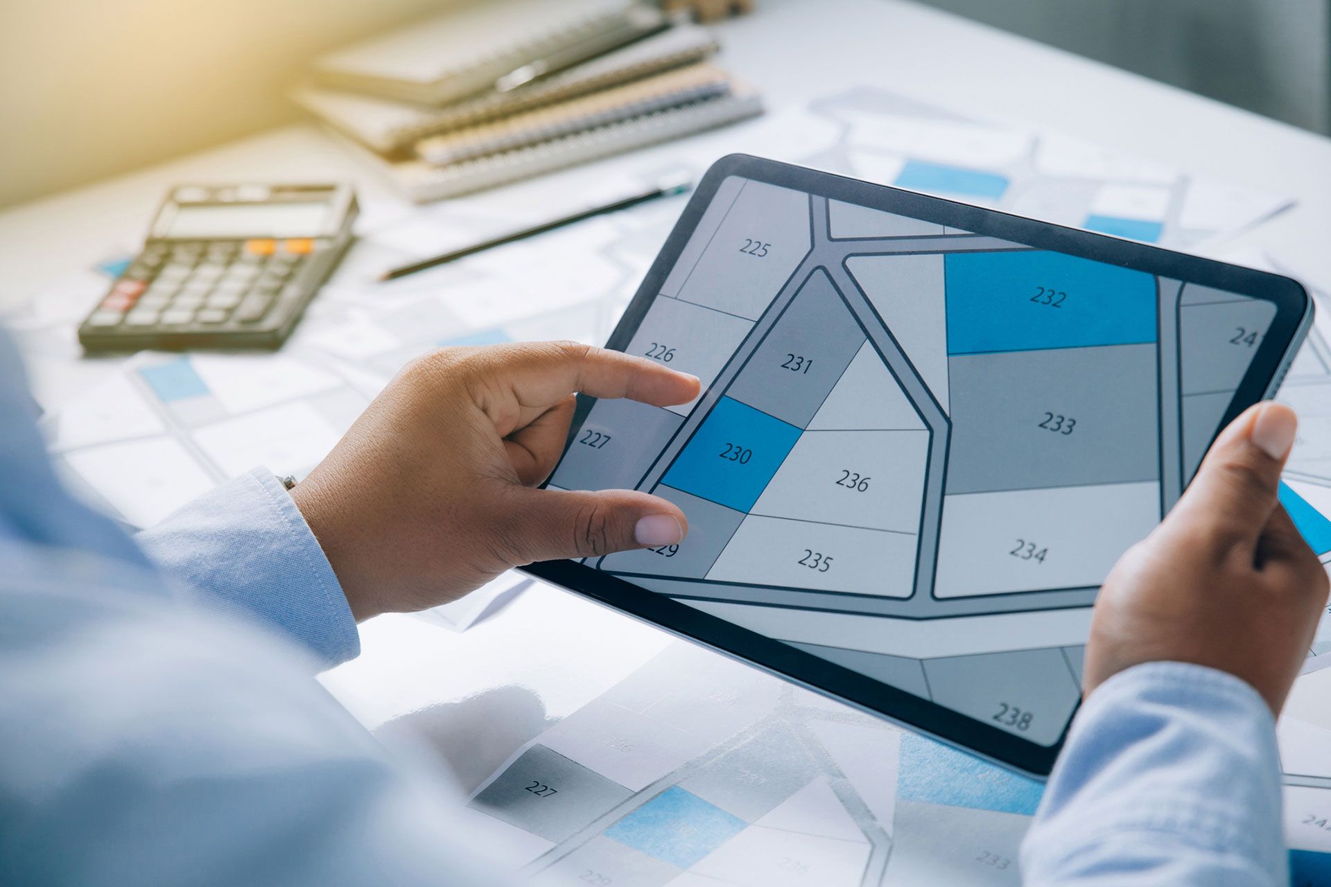 Man holding a tablet looking at lots of lands. Land plot management - real estate concept with vacant land for building construction and housing subdivision for sale, rent, buy, or investment