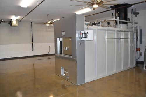 Large industrial HVAC unit in a polished basement room with white walls and ceiling fans