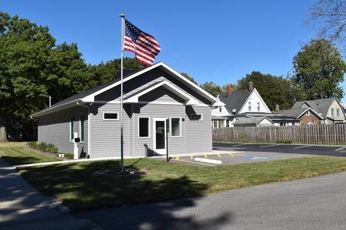 Small gray building with an American flag flying outside on a sunny day