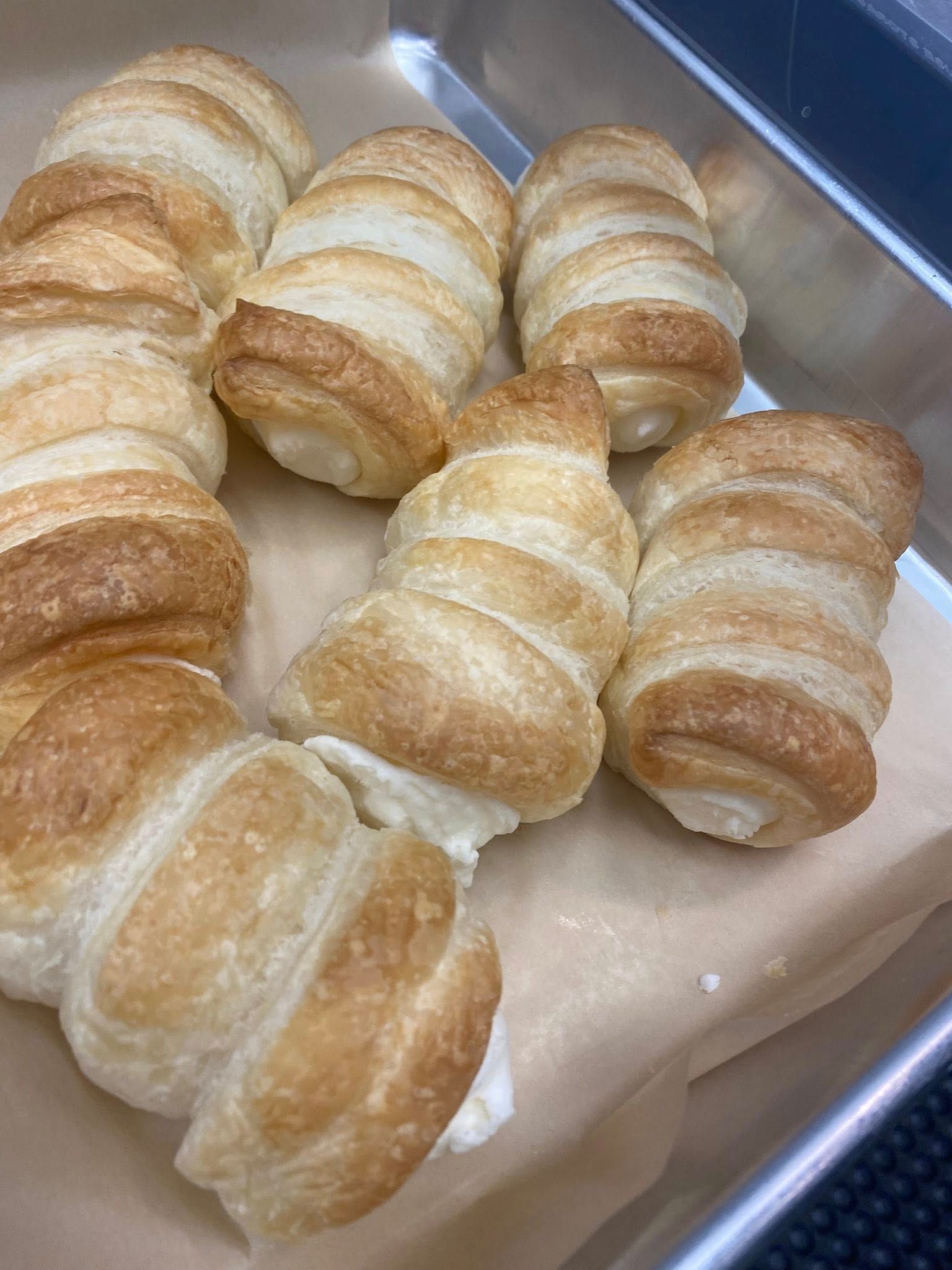 Tray of crescent-shaped pastries dusted with sugar, arranged on parchment paper.