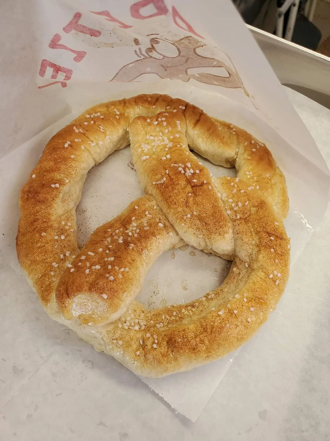 Sugar-coated pretzel on a paper bag on a tabletop.