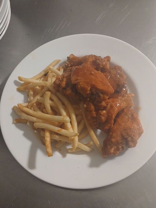 Plate of buffalo wings and french fries on a white plate.
