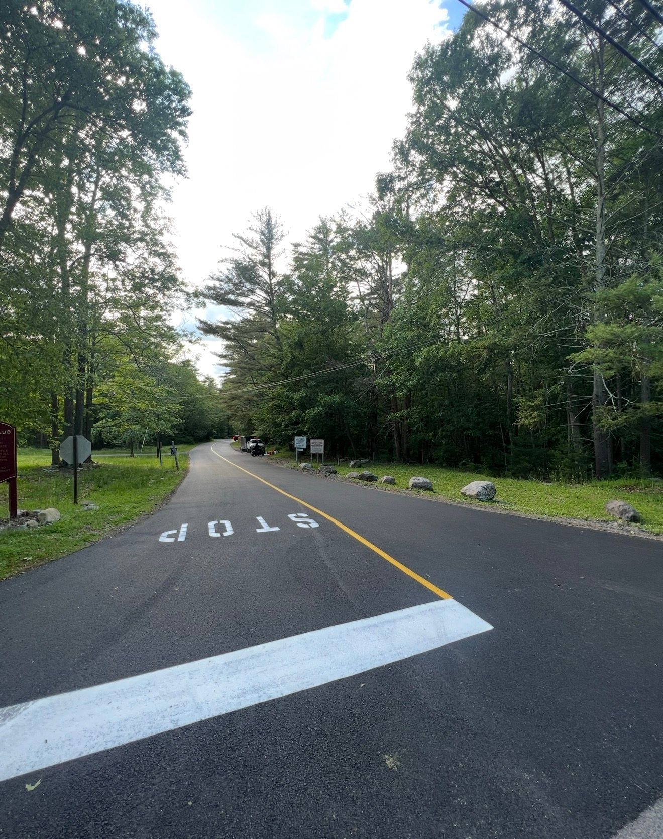 A paved path winds through a green, wooded area with a 