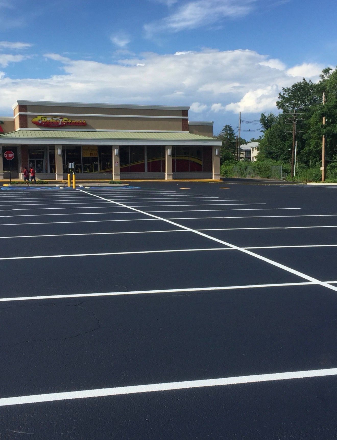 An empty parking lot with freshly painted white lines in front of a commercial building under a blue sky.