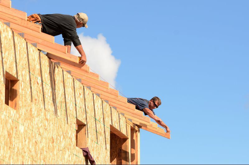 Two men are working on the roof of a house.