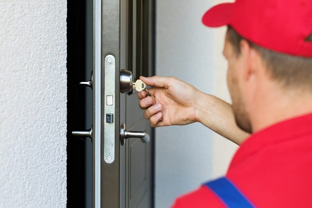 A Man in A Red Hat Is Opening a Door with A Key — East Coast Locksmiths in Wauchope, NSW