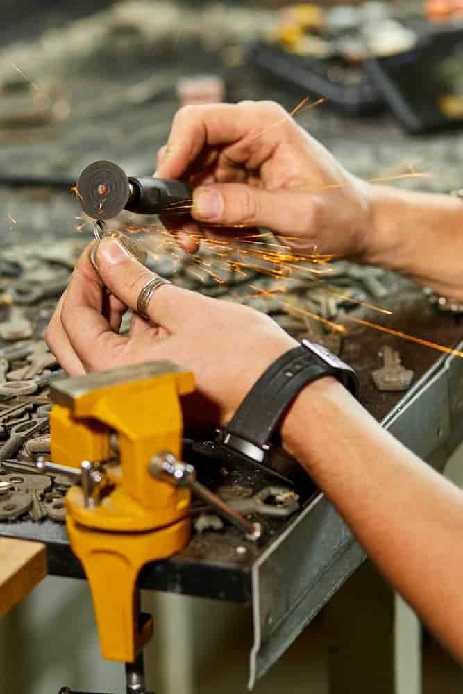 A Person Is Working on A Piece of Metal in A Workshop — East Coast Locksmiths in Lake Cathie, NSW