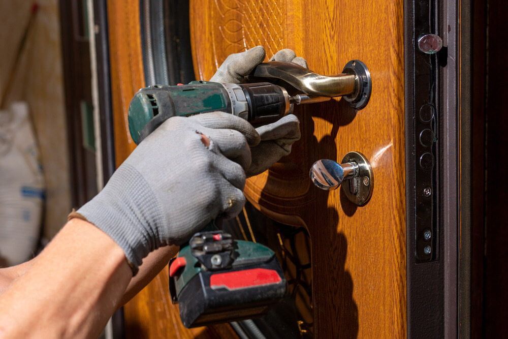 A Person Is Using a Drill to Fix a Door Handle — East Coast Locksmiths in Port Macquarie, NSW
