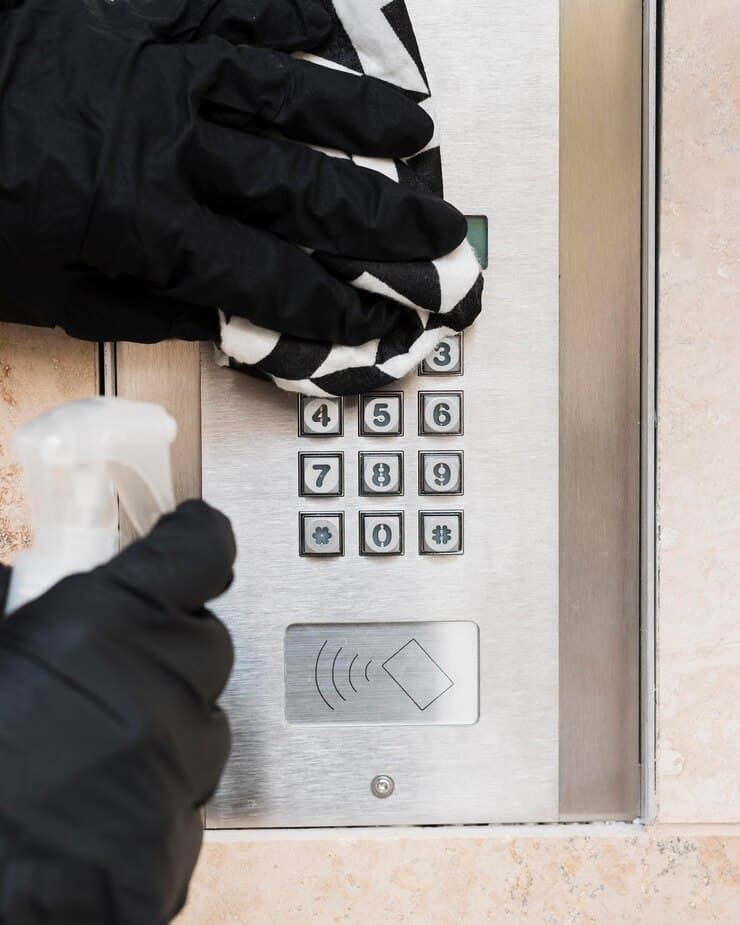 A Person Wearing Black Gloves Is Cleaning a Keypad with A Cloth — East Coast Locksmiths in Wauchope, NSW