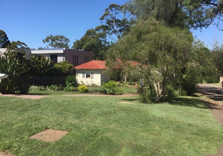 A House With a Red Tile Roof is Surrounded by Trees and Grass — Superior Turf in Oak Flats, NSW