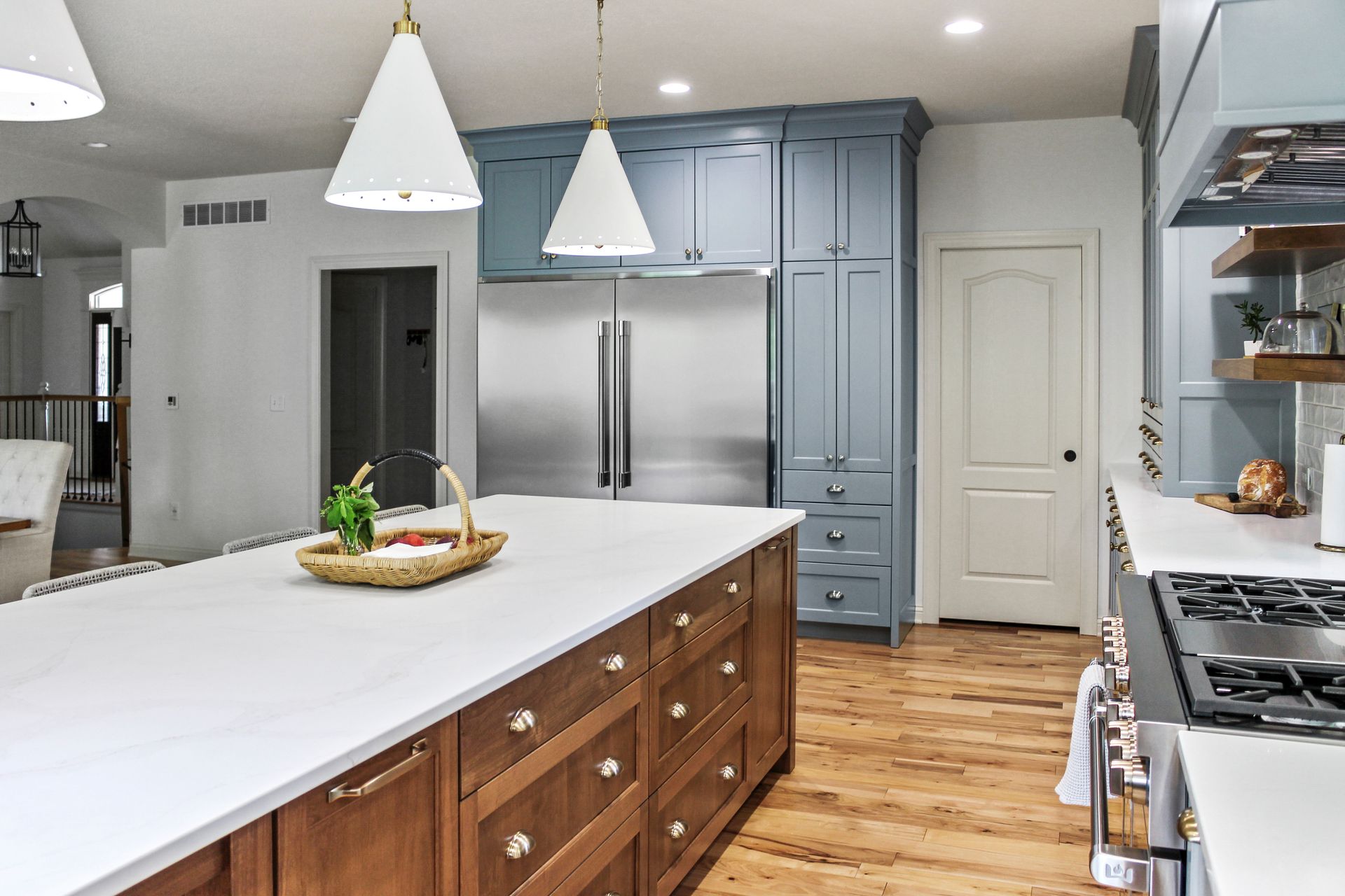 Transitional kitchen with natural wood island, custom blue cabinetry surround, and quartz countertops in a Columbia MO home. 