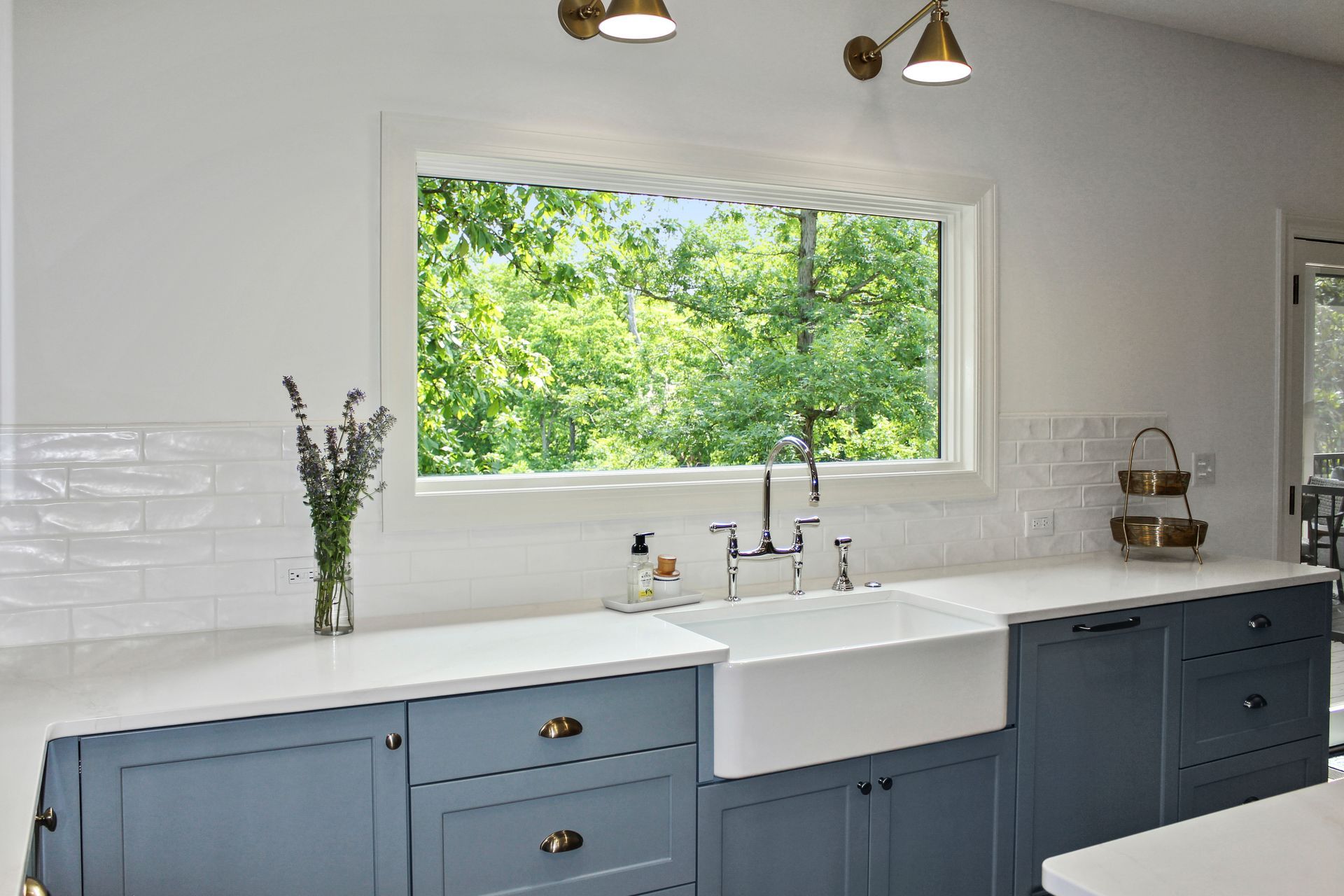 A custom kitchen with blue cabinets , a farmhouse sink , and a large window. Custom cabinets Columbia Missouri 