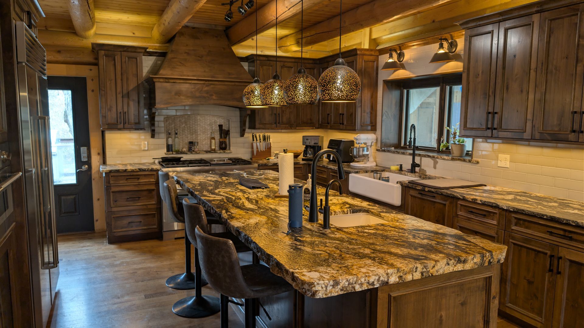 Rustic custom wood kitchen cabinets with matching range hood, granted island, and exposed beam ceilings in Mid- Missouri. Custom cabinets Columbia Missouri 