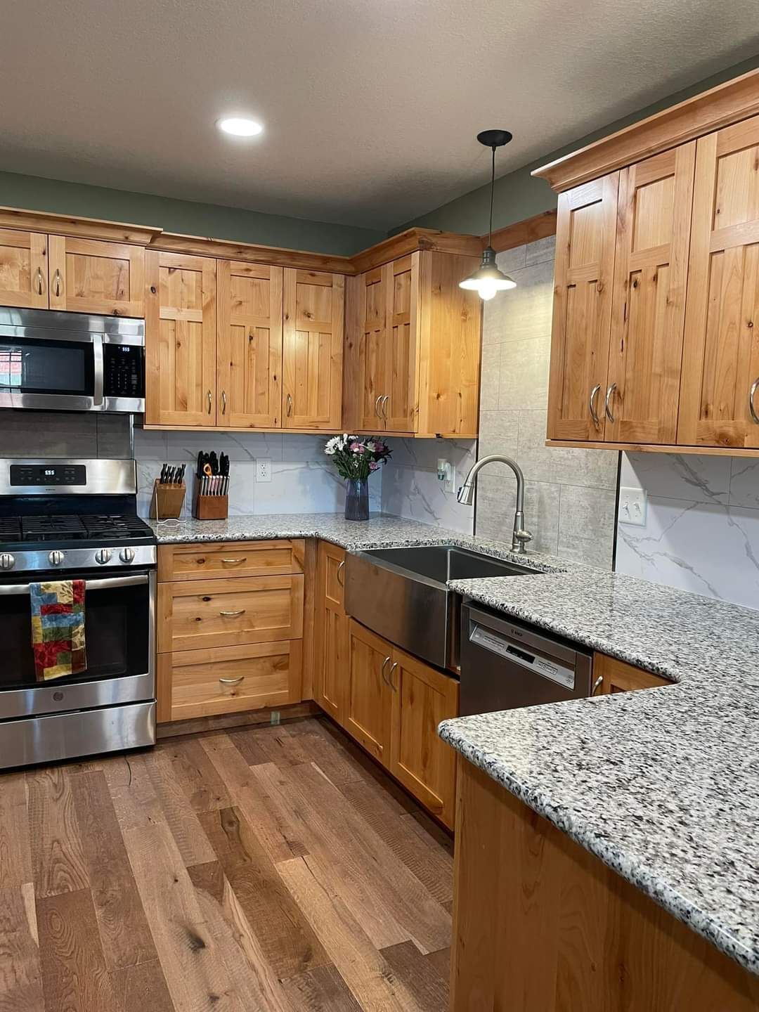 Traditional natural wood custom kitchen cabinetry with granite countertops and stainless steel farmhouse sink in a Williamsburg MO home. 