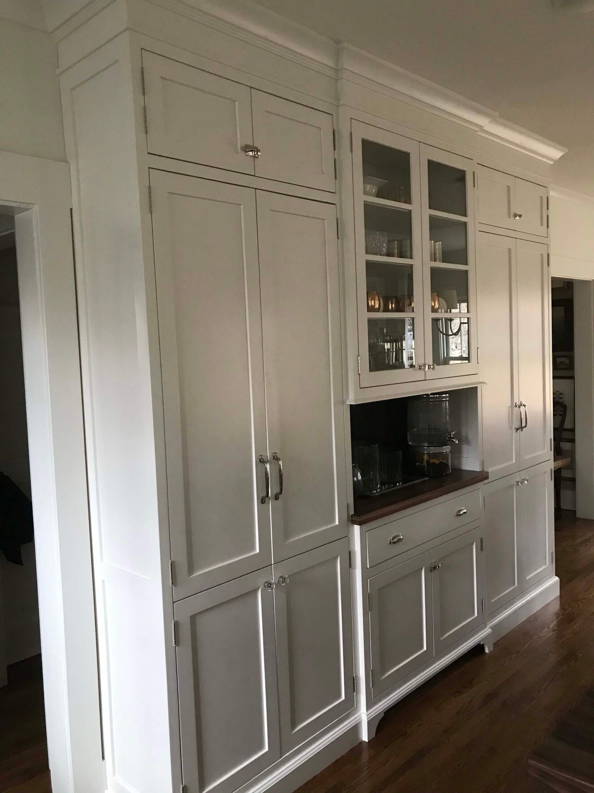 A kitchen with white cabinets and glass doors. Custom cabinets Columbia Missouri 