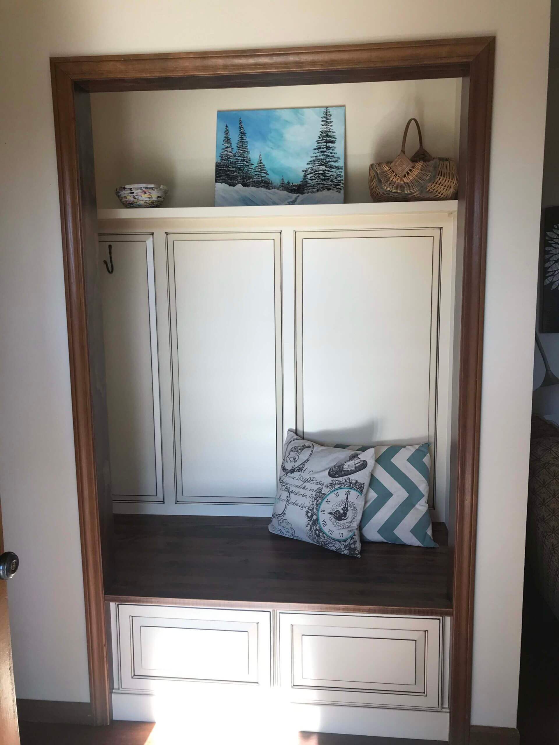 A closet with a bench and a painting on the wall. Custom cabinets Columbia Missouri 