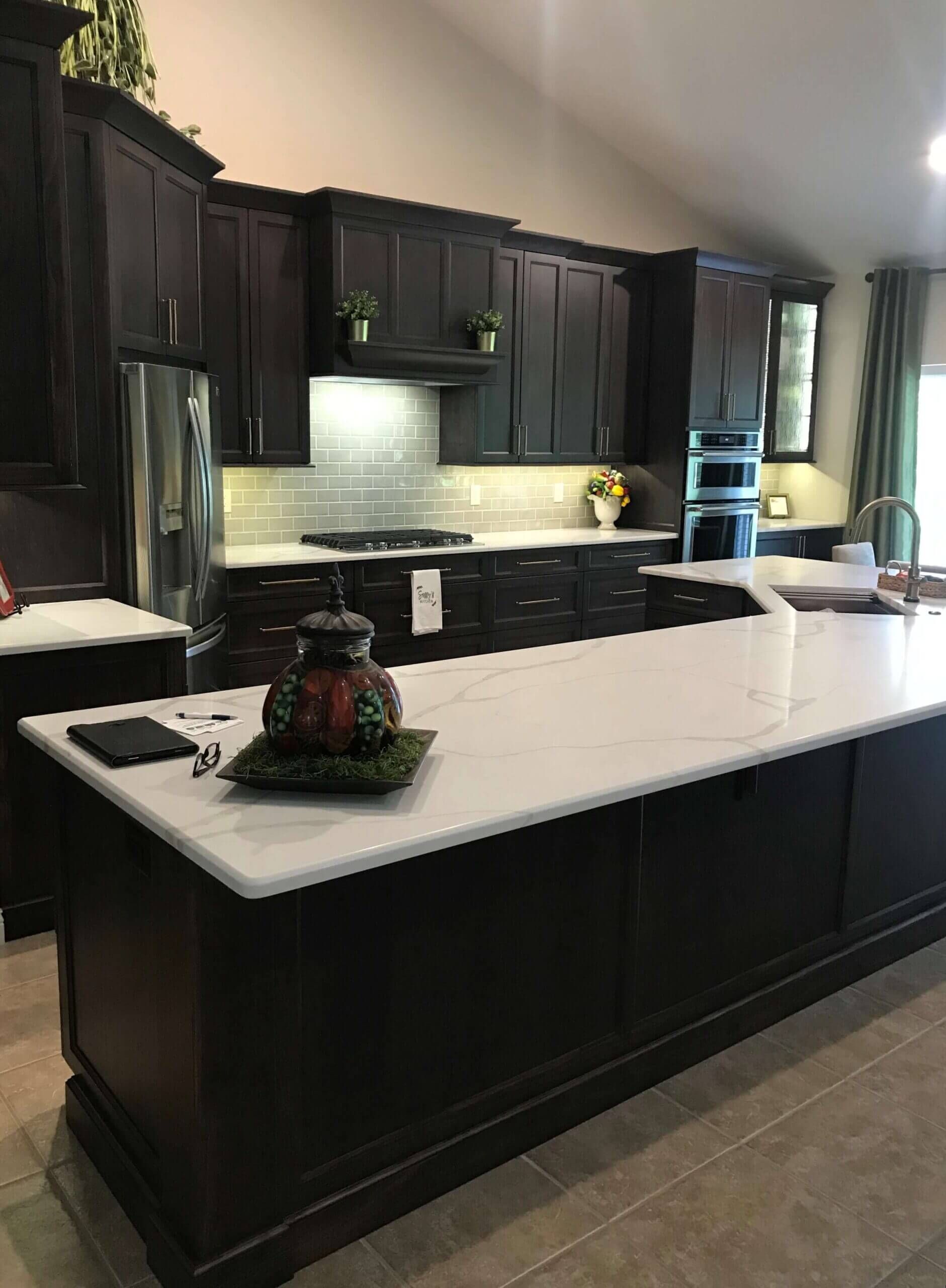 A custom kitchen with black cabinets and white counter tops and a large island in Mid- Missouri.
