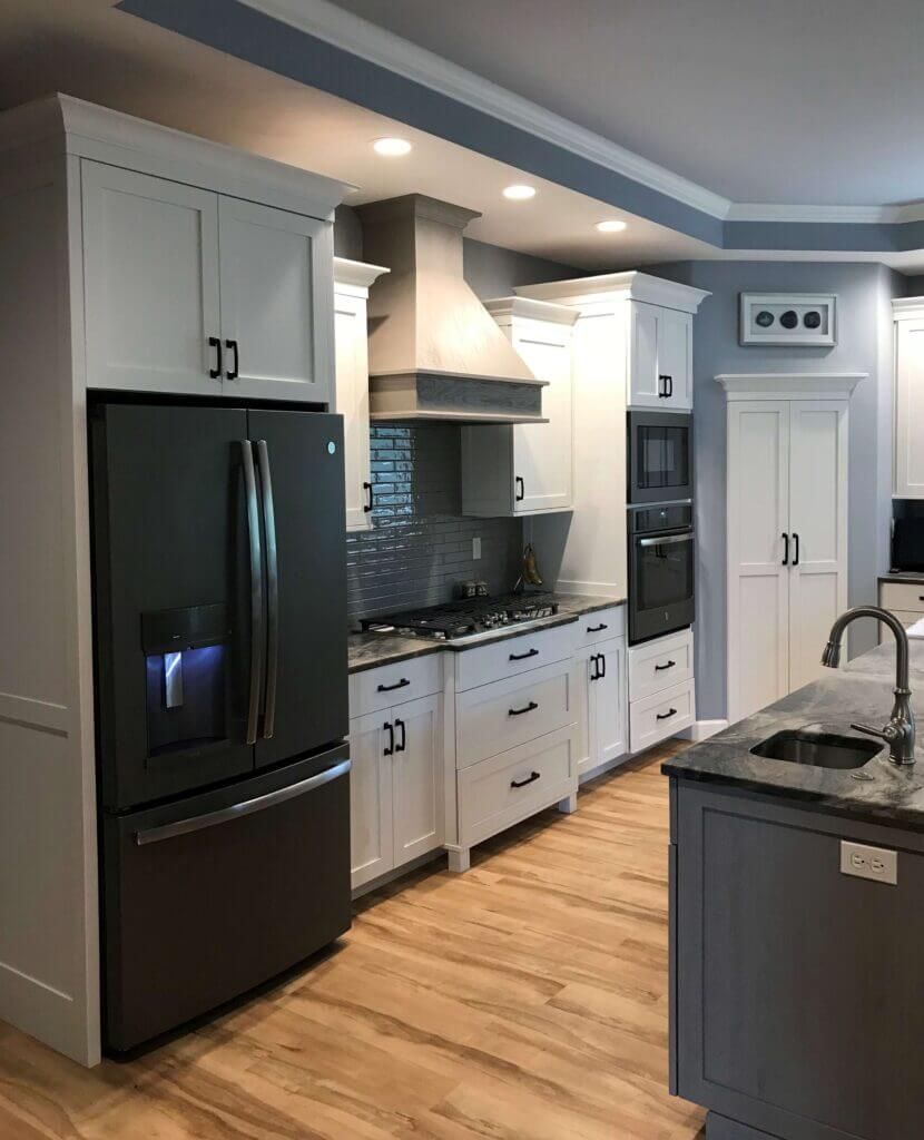 A kitchen with white cabinets , a black refrigerator , a stove , and a sink. Custom cabinets Columbia Missouri 