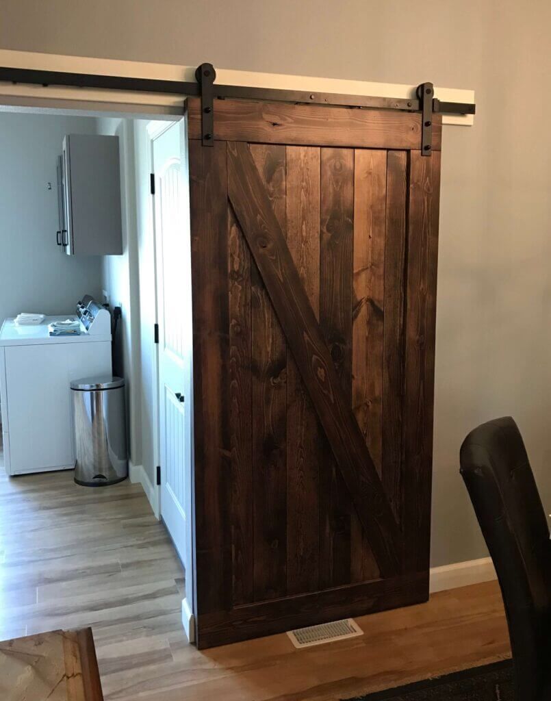 A wooden sliding barn door is open to a laundry room.