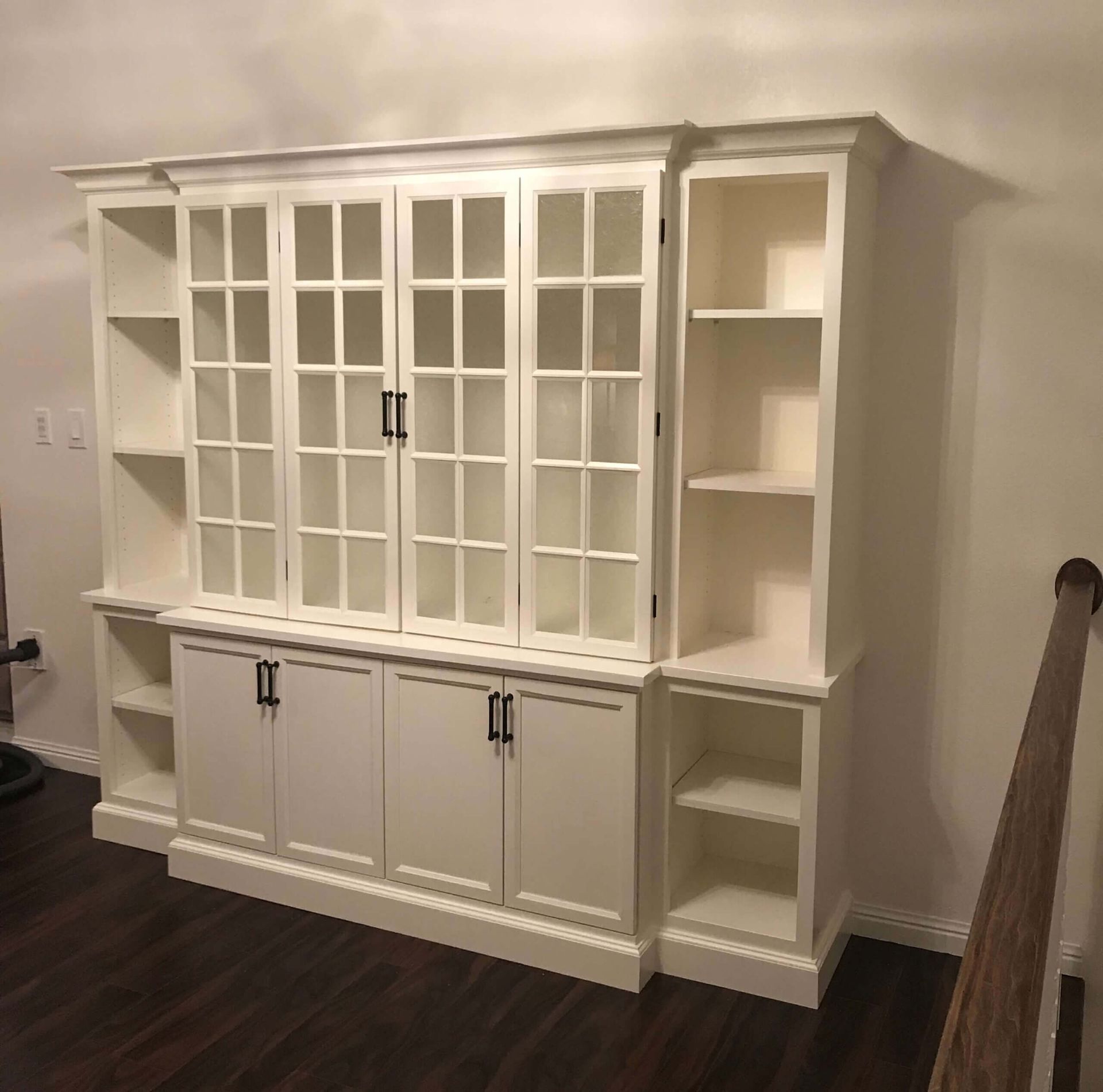 A large white cabinet with glass doors and shelves in a living room. Custom cabinets Columbia Missouri 