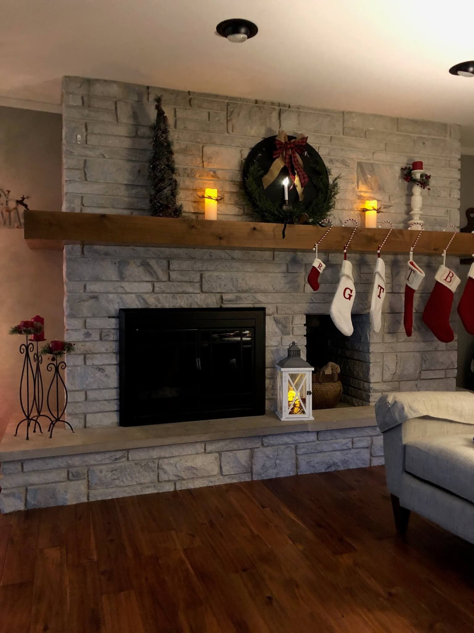 A living room with a fireplace with custom mantel and stockings on the mantle
