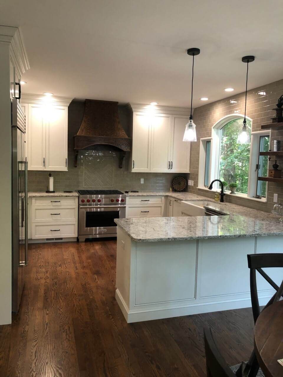 A kitchen with custom white cabinets, stainless steel appliances, granite counter tops and hardwood floors.