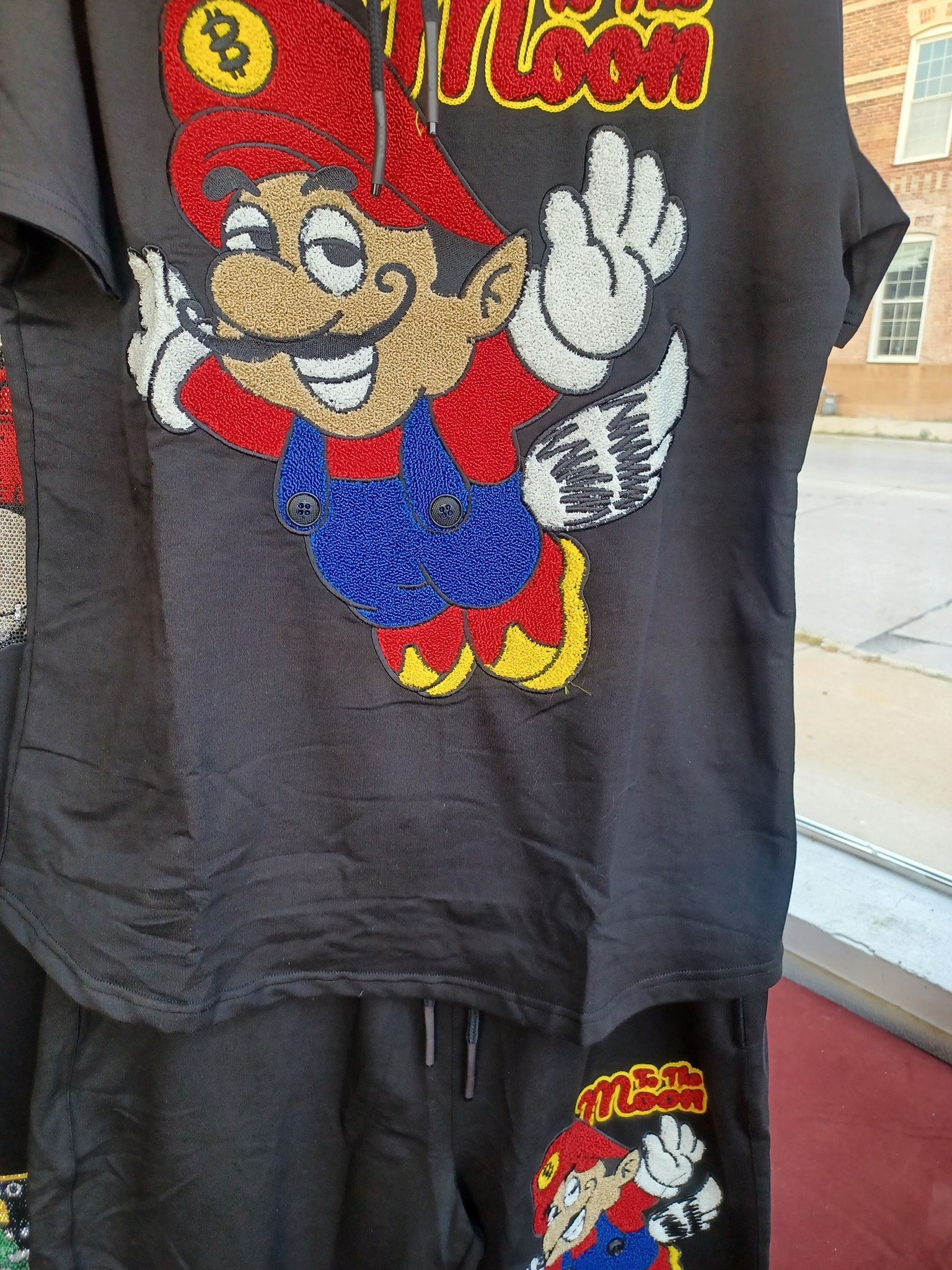 Black t-shirt and shorts set with sequined Mario character graphic. Mario is smiling, wearing a red hat and blue overalls.