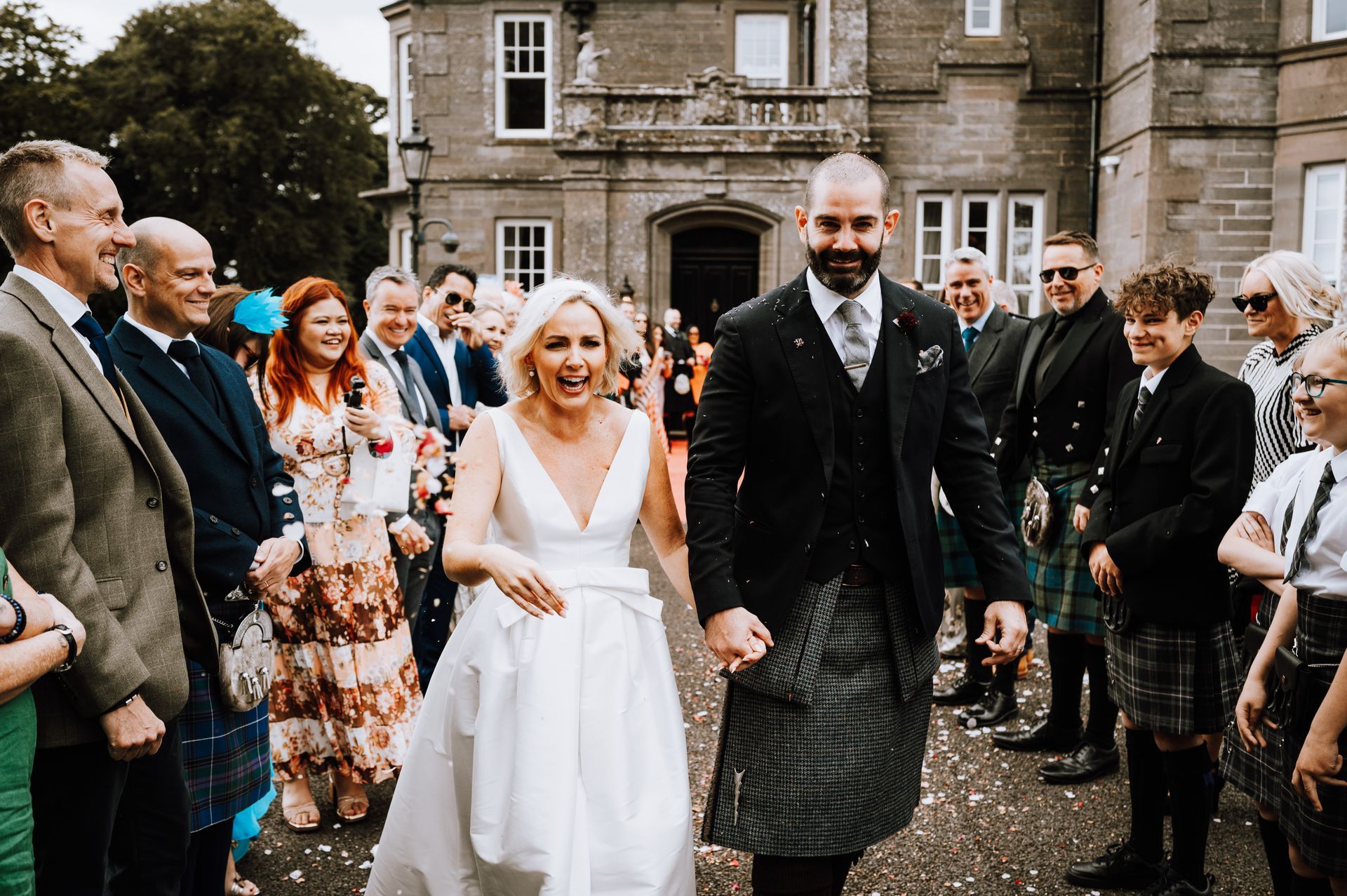 Kelly Lundberg and her husband walk hand in hand after their wedding ceremony as guests celebrate around them. Instead of traditional wedding gifts, the couple invited guests to donate to The Sparkle Foundation in support of children and families in Malawi.