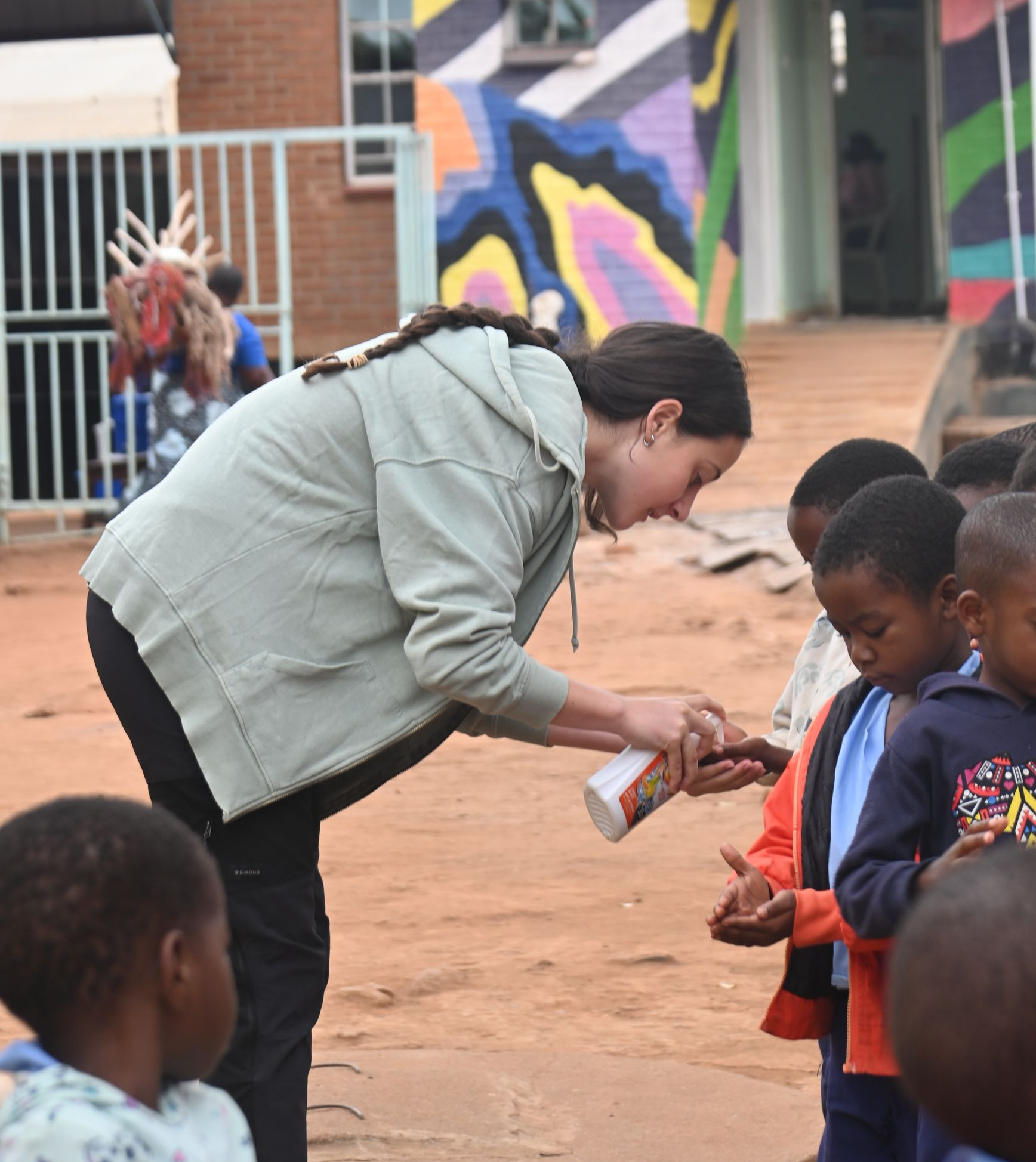 Luce, a volunteer with The Sparkle Foundation, applies hand soap to children’s hands as they prepare to wash their hands during her volunteer experience in Malawi.