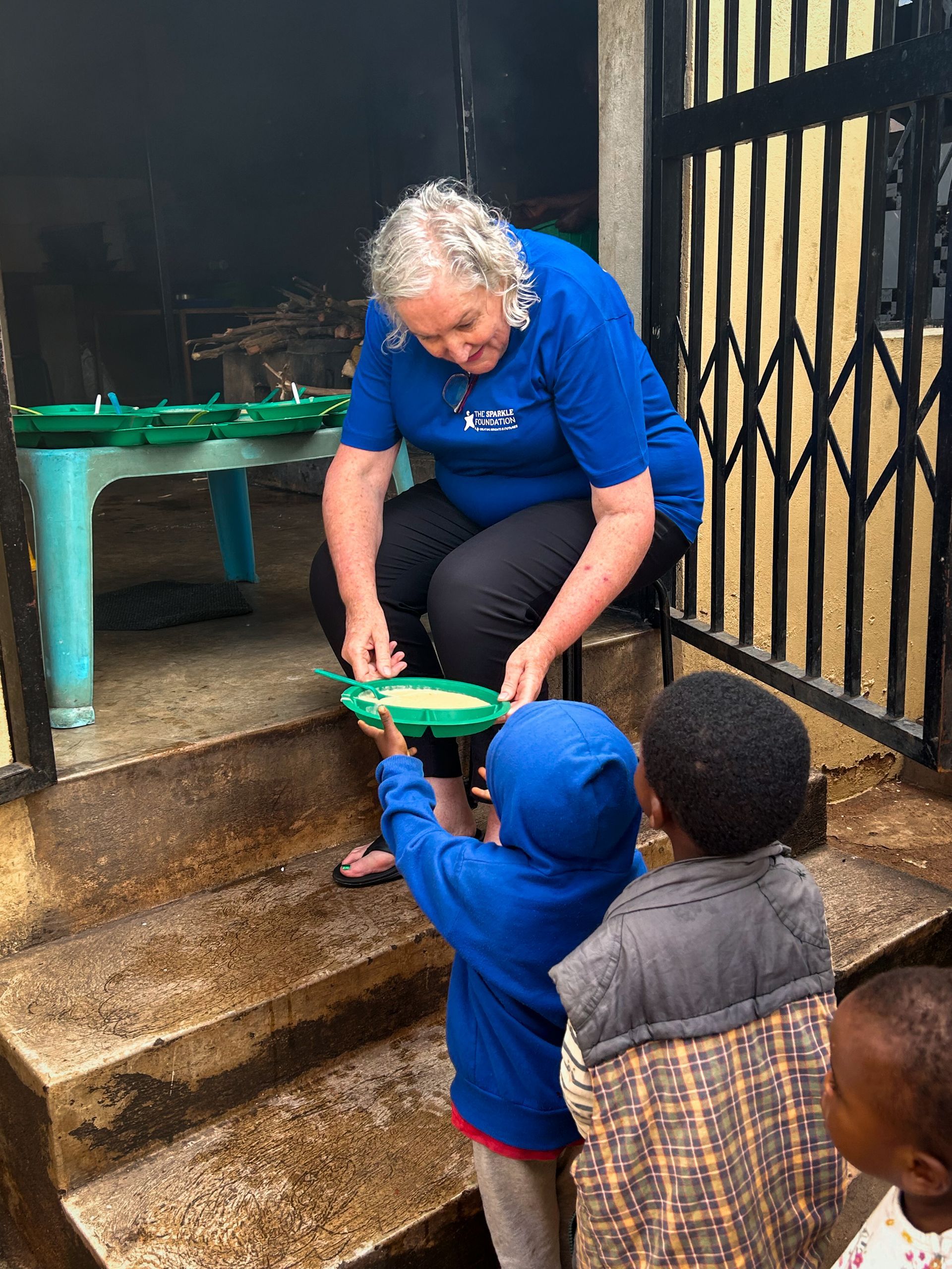 Leith serving breakfast porridge to children during the morning feeding programme, helping ensure they begin the day with a warm meal before classes and activities.