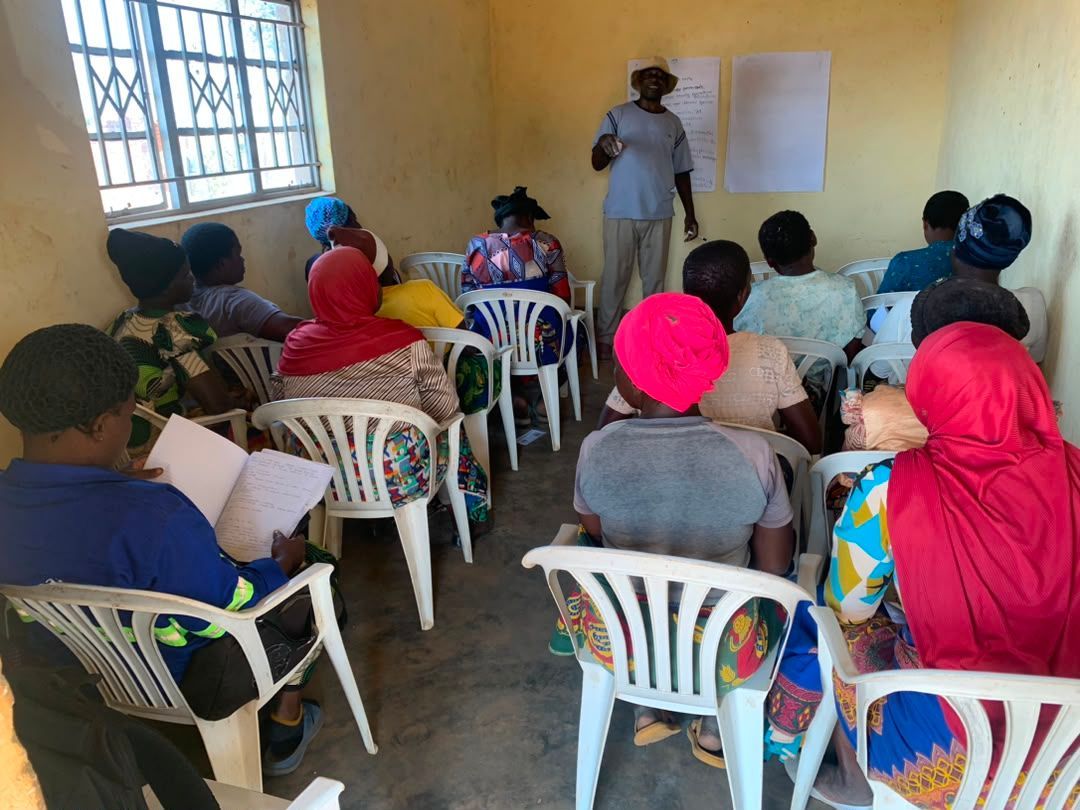 Women from Sakata village, Zomba District, attend a classroom session on regenerative agriculture as part of The Sparkle Foundation's Spark to Success programme, listening to a trainer explain practical approaches to soil health and sustainable farming.