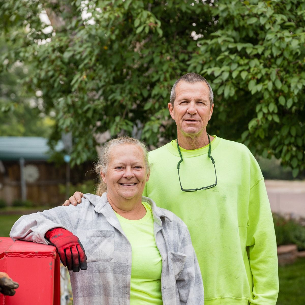 A man and a woman are posing for a picture in front of a tree.