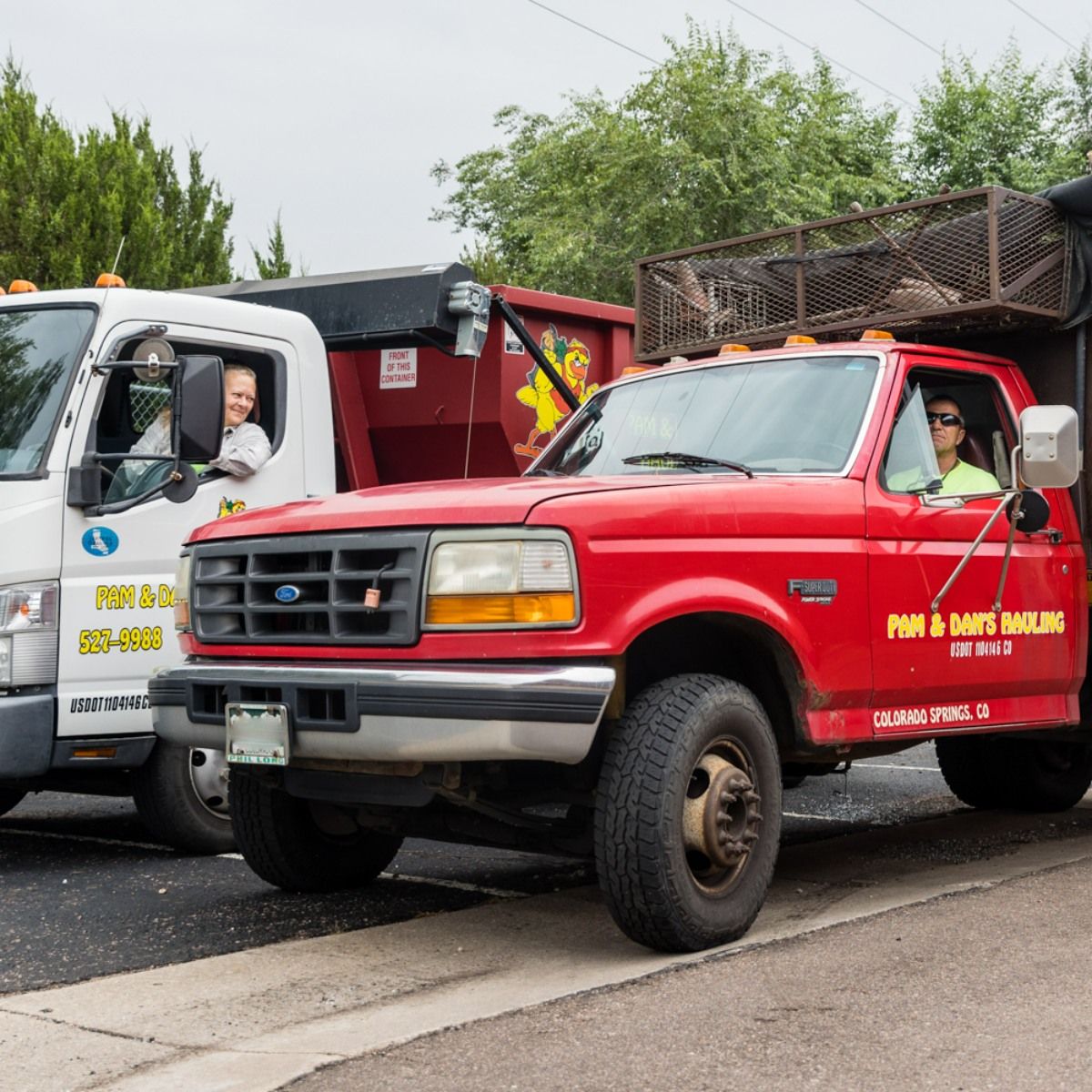 A red truck is parked next to a white truck