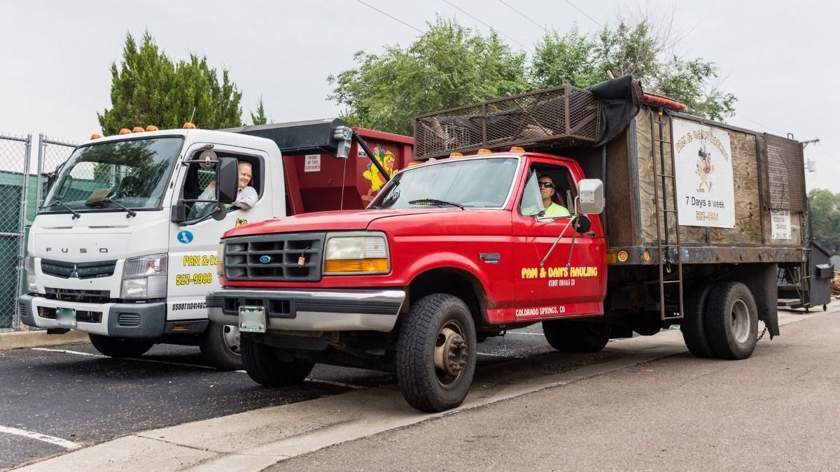 Two garbage trucks are parked next to each other on the side of the road.