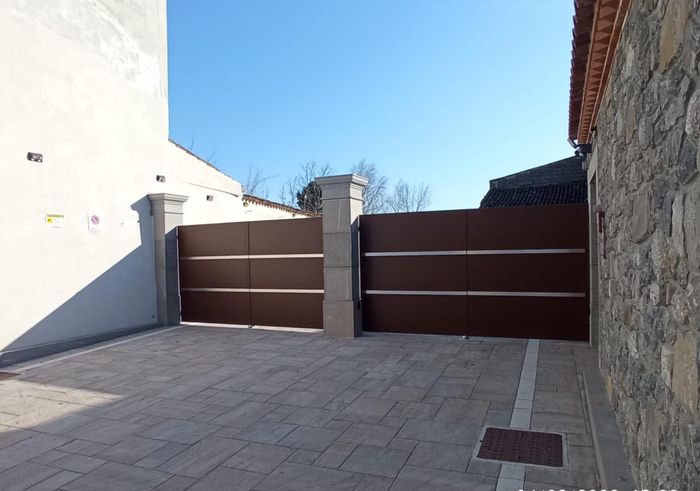 Un muro di pietra con un cancello marrone davanti