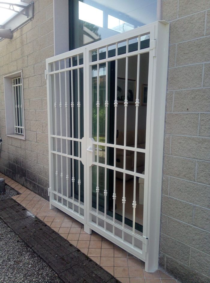 Un cancello bianco si trova sul lato di un edificio di mattoni.