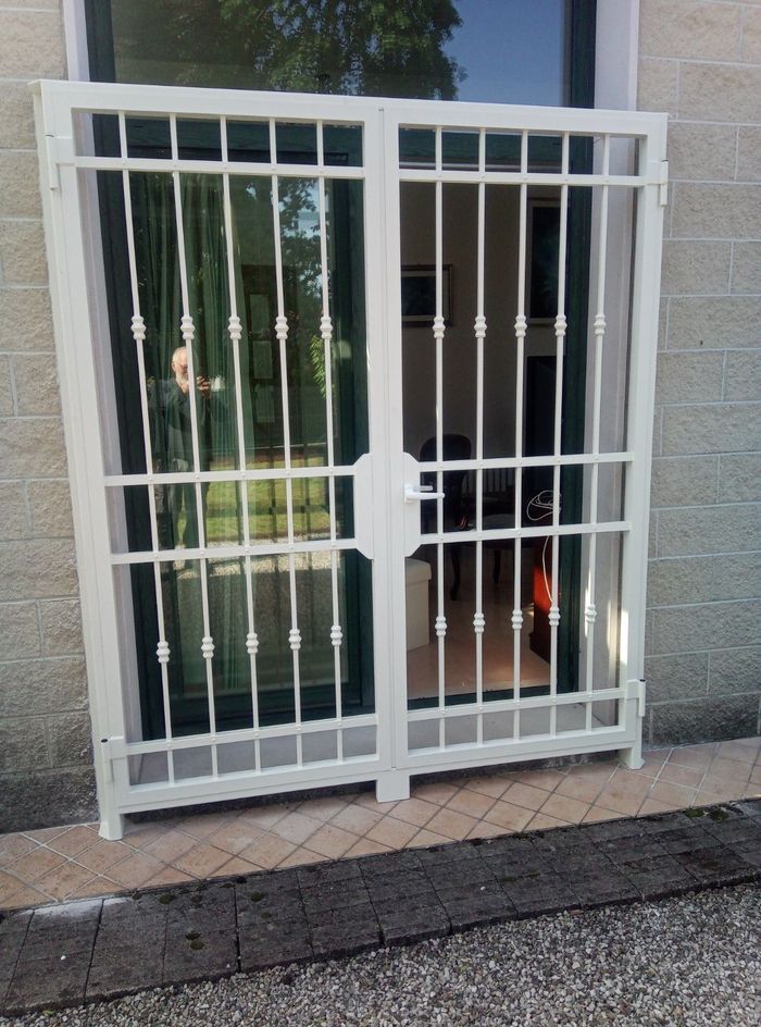 Una porta bianca con una recinzione in ferro battuto attorno